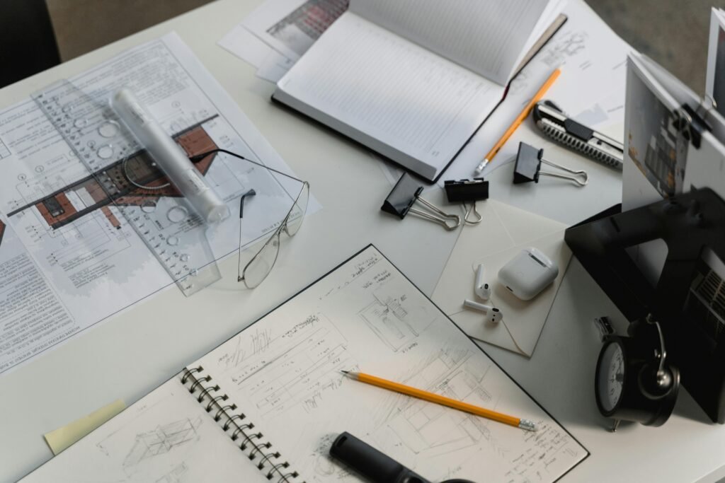 pexels-photo-6615230-6615230 A busy architectural workspace featuring blueprints, sketches, and drafting tools.